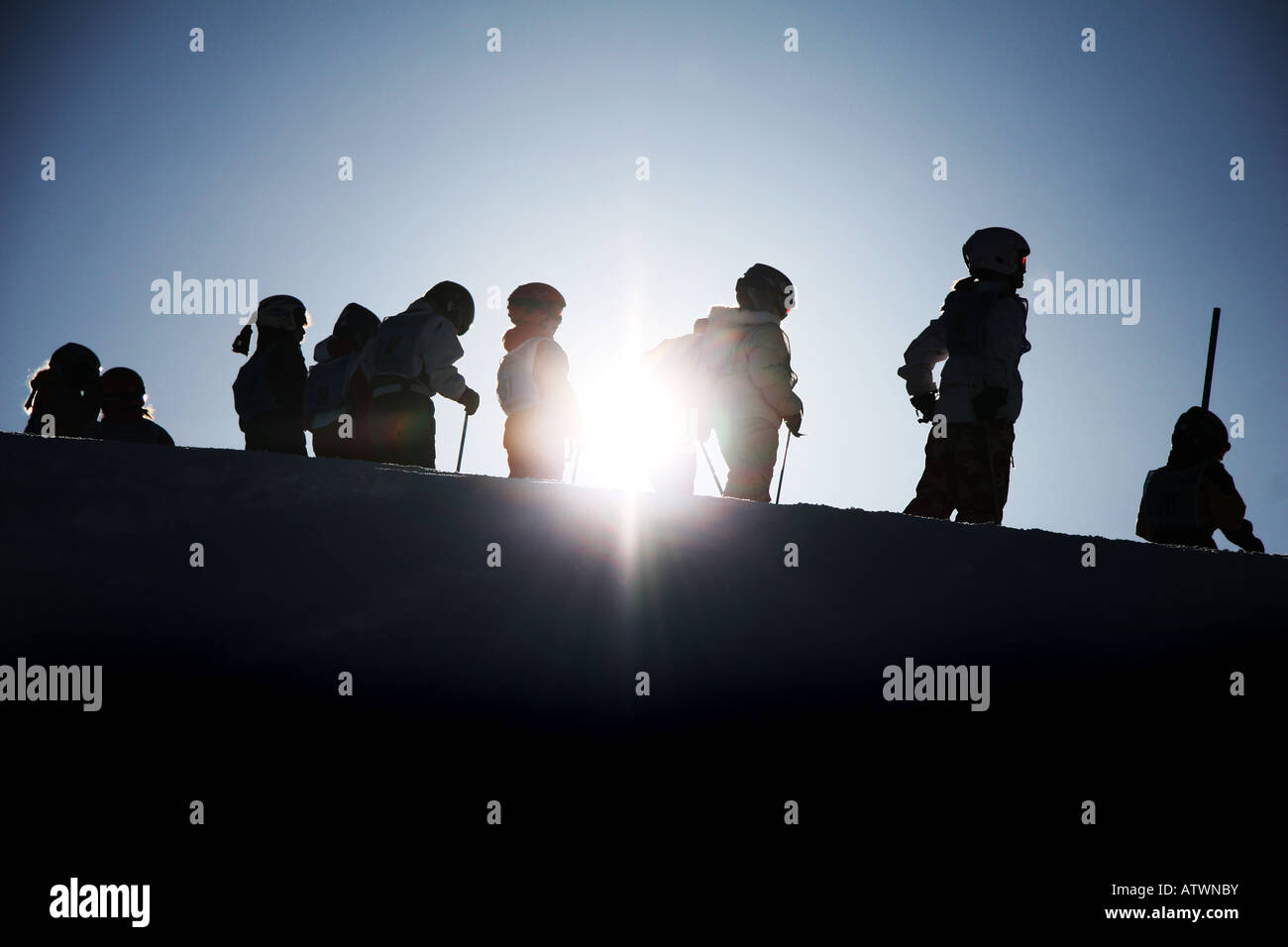 Ski school class silhouetted against alpine sun Stock Photo