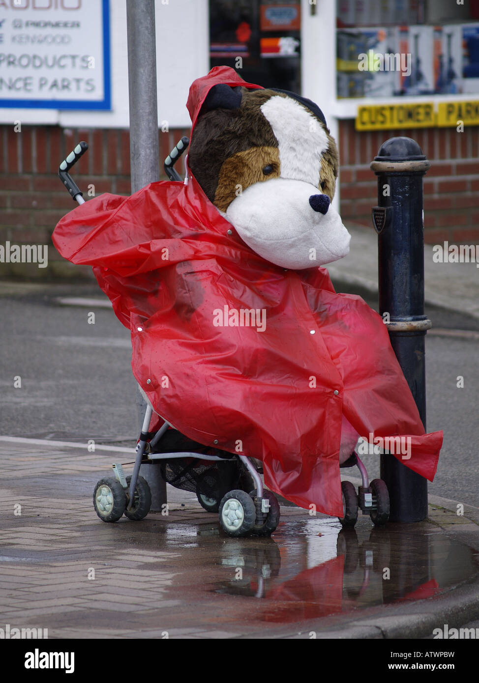 Large toy dog cuddly toy in a pushchair with a rain coat on Stock Photo