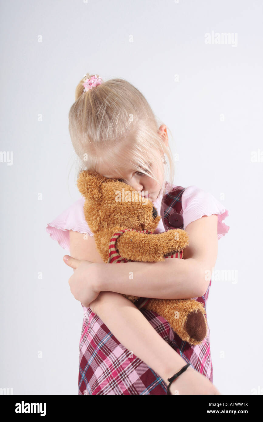 A very sad small girl holding her teddy bear Stock Photo