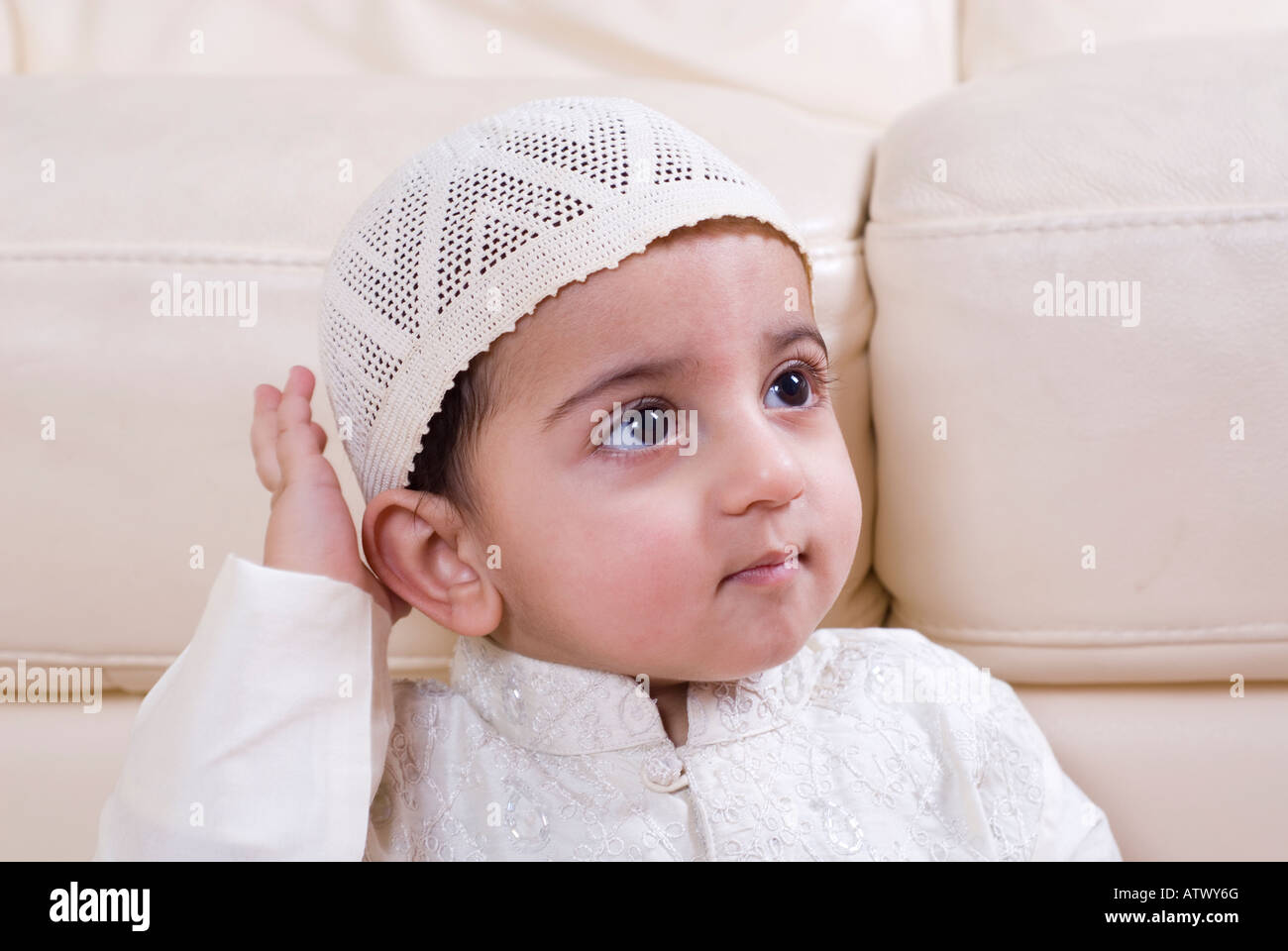 Cute Muslim baby in traditional Islamic clothing looking up hand ...