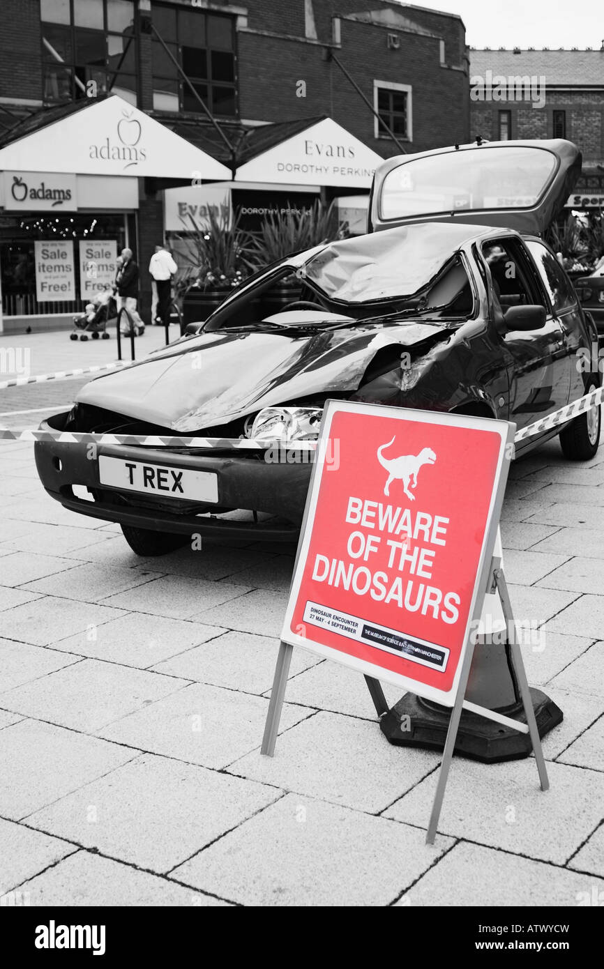a crushed car with a sign saying beware of the dinosaurs merseyway ATWYCW