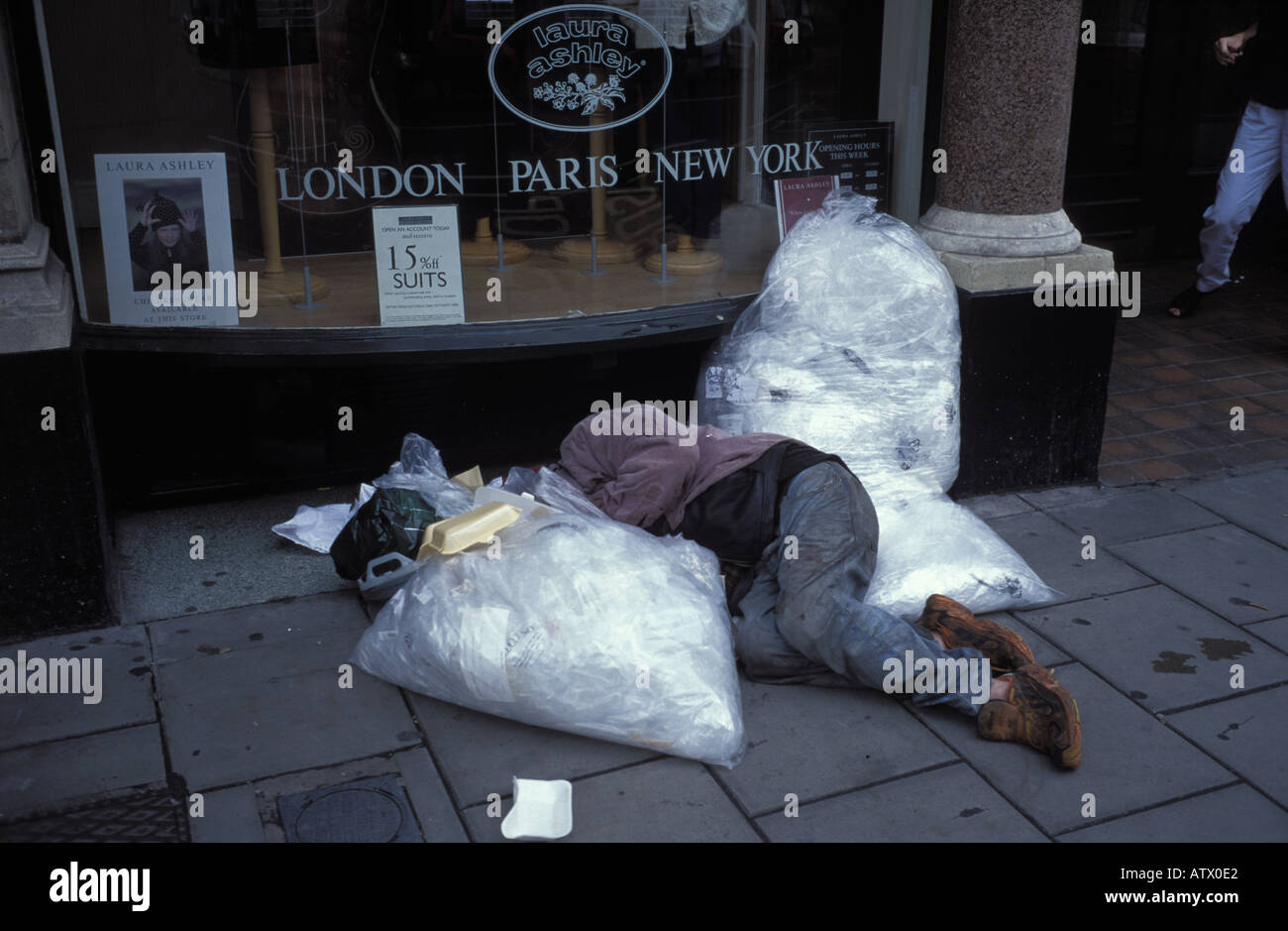 Drunk or homeless sleeping man in street by Laura Ashley Shop in Bristol England Stock Photo