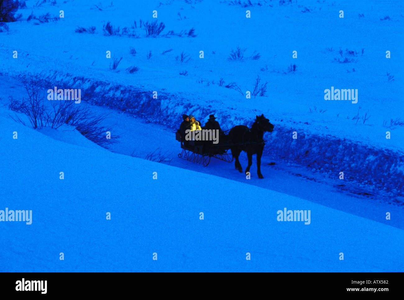 A couple ride down a snowy lane in a one horse sleigh Crested Butte Colorado Stock Photo