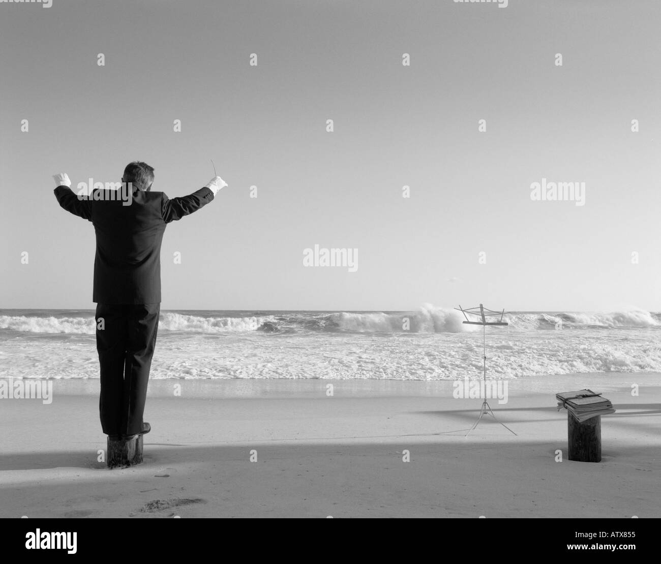 Man 40-44, 45-49, 50-54, 55-60, 60-65, 65-69, years old, conducting invisible orchestra at beach (rear view), Hamptons, New York, USA Stock Photo