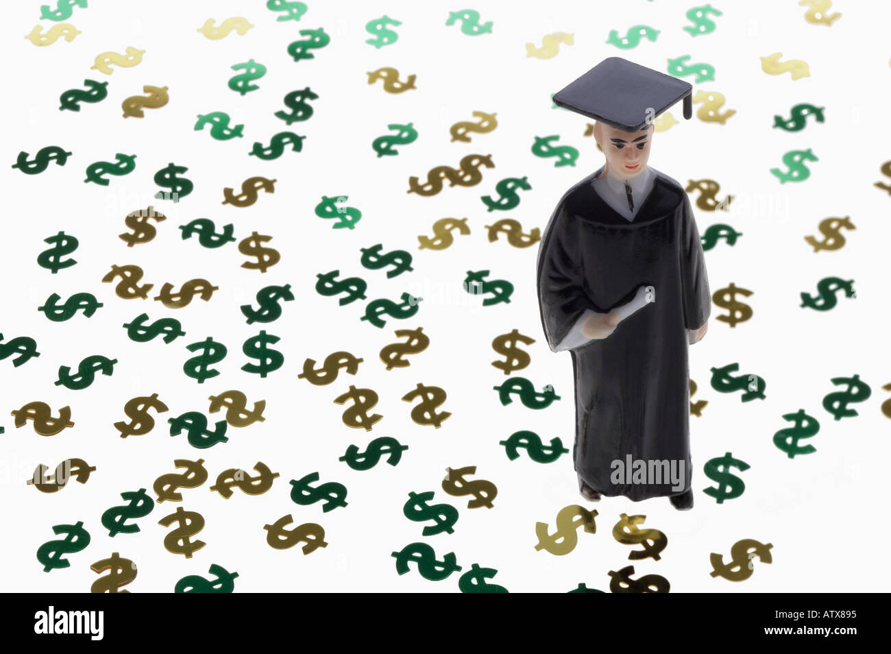 Still life of a graduate figurine standing in a sea of dollar signs  symbolizing the high cost of education Stock Photo