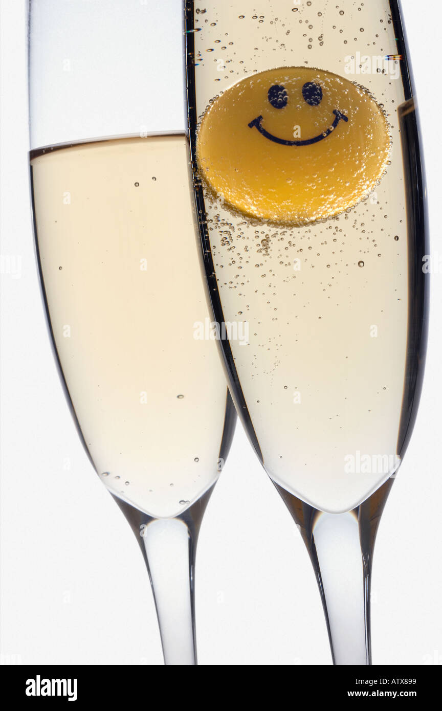 Still life of two glasses of champagne on a white background with a happy face floating inside Stock Photo