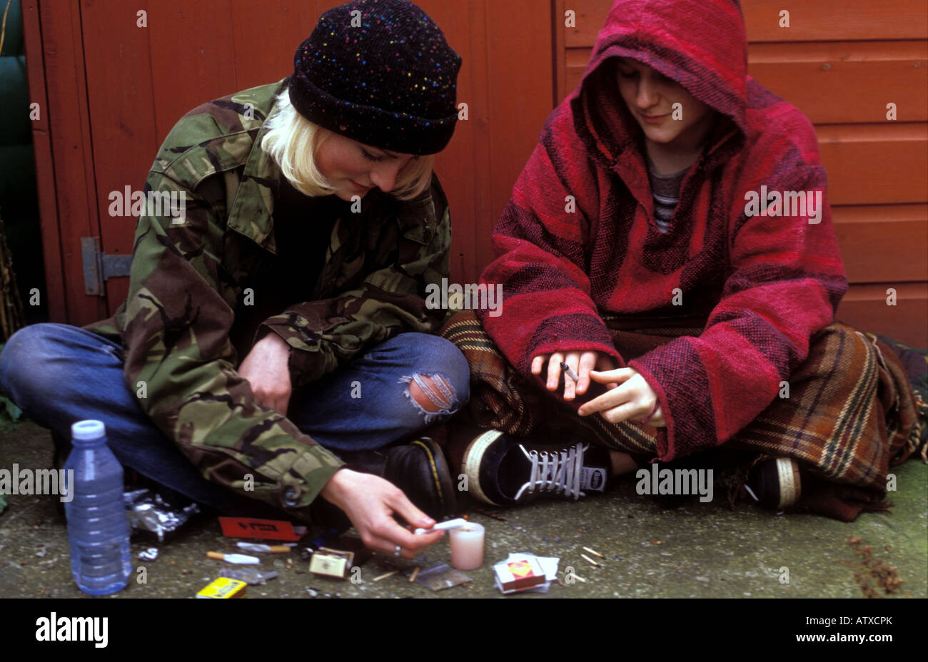 Two young women smoking cannabis and snorting cocaine in a back street. Stock Photo