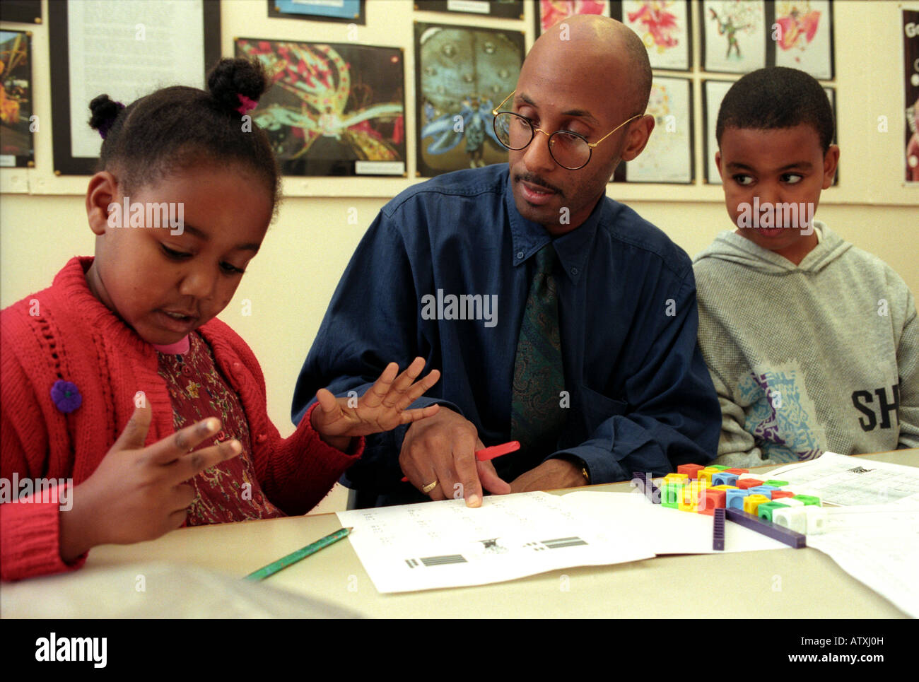 Male Primary School Teacher Helping Children With Maths Lesson Stock male-primary-school-teacher-helping-children-with-maths-lesson-stock