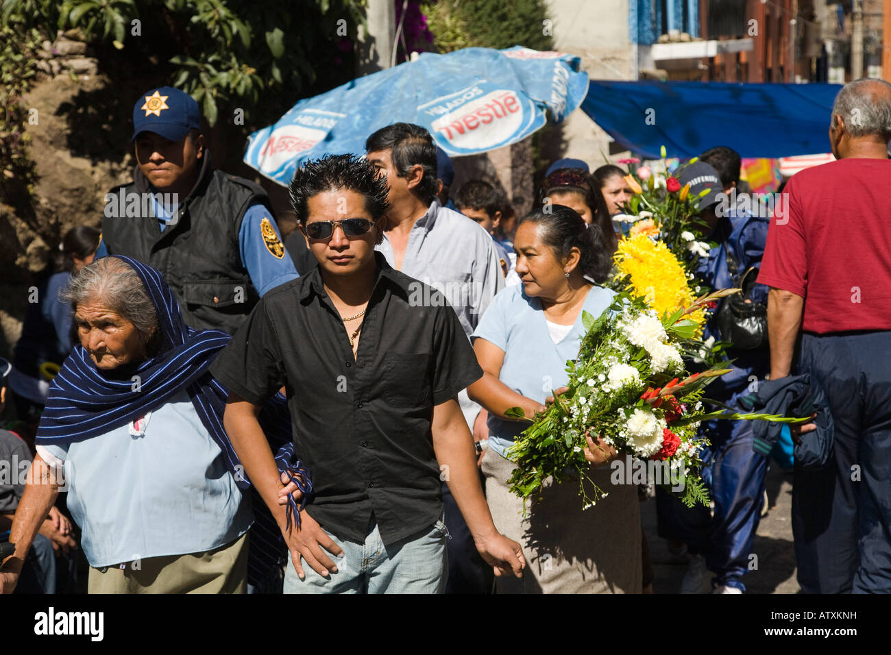 MEXICO Guanajuato Mexican men and woman grandmothers and teens walking toward cemetery Day of the Dead celebration bouquets Stock Photo