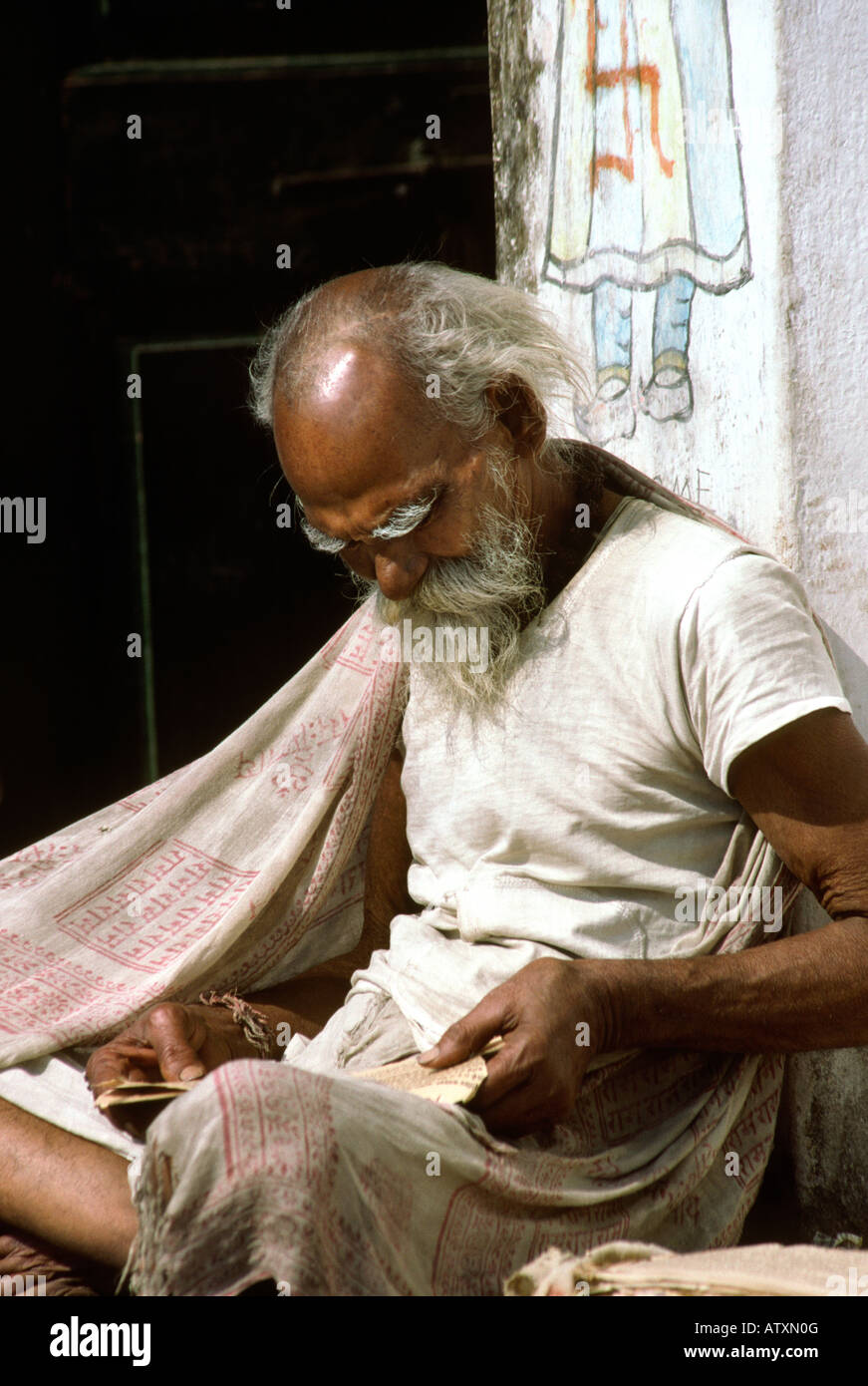 India Rajasthan Udaipur man reading newspaper sitting outside decorated house Stock Photo