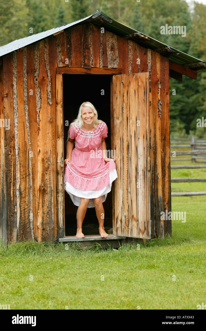 Woman exiting an outhouse Stock Photo