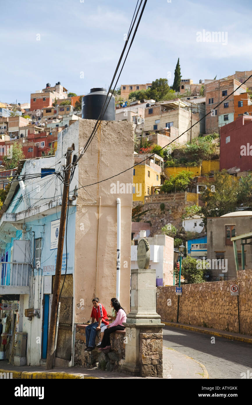 MEXICO Guanajuato Mexican teenagers sitting on wall narrow building between two streets buildings on hillside Stock Photo