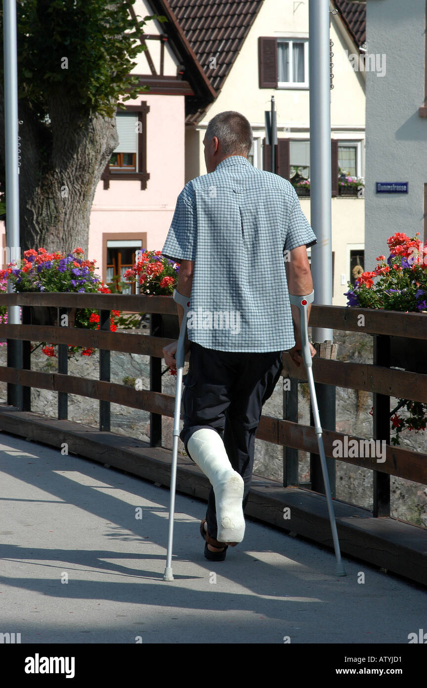 Mann Gipsbein Kruecken gehbehindert Genesung Reha Erholung Spaziergang Arztbesuch Verletzung Stock Photo