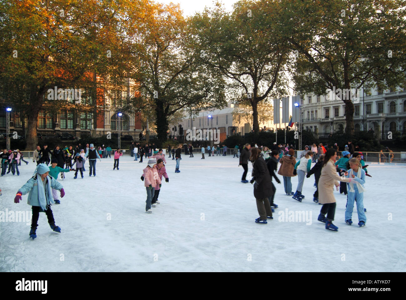 Adults children & kids on ice skates at Christmas winter ice skating rink at Natural History Museum building South Kensington West London England UK Stock Photo