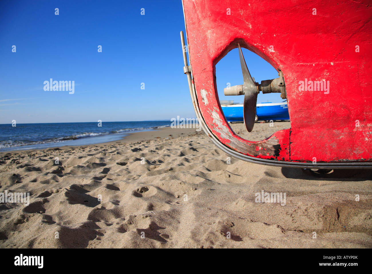 red fishing boat pulled up on sandy beach Stock Photo - Alamy