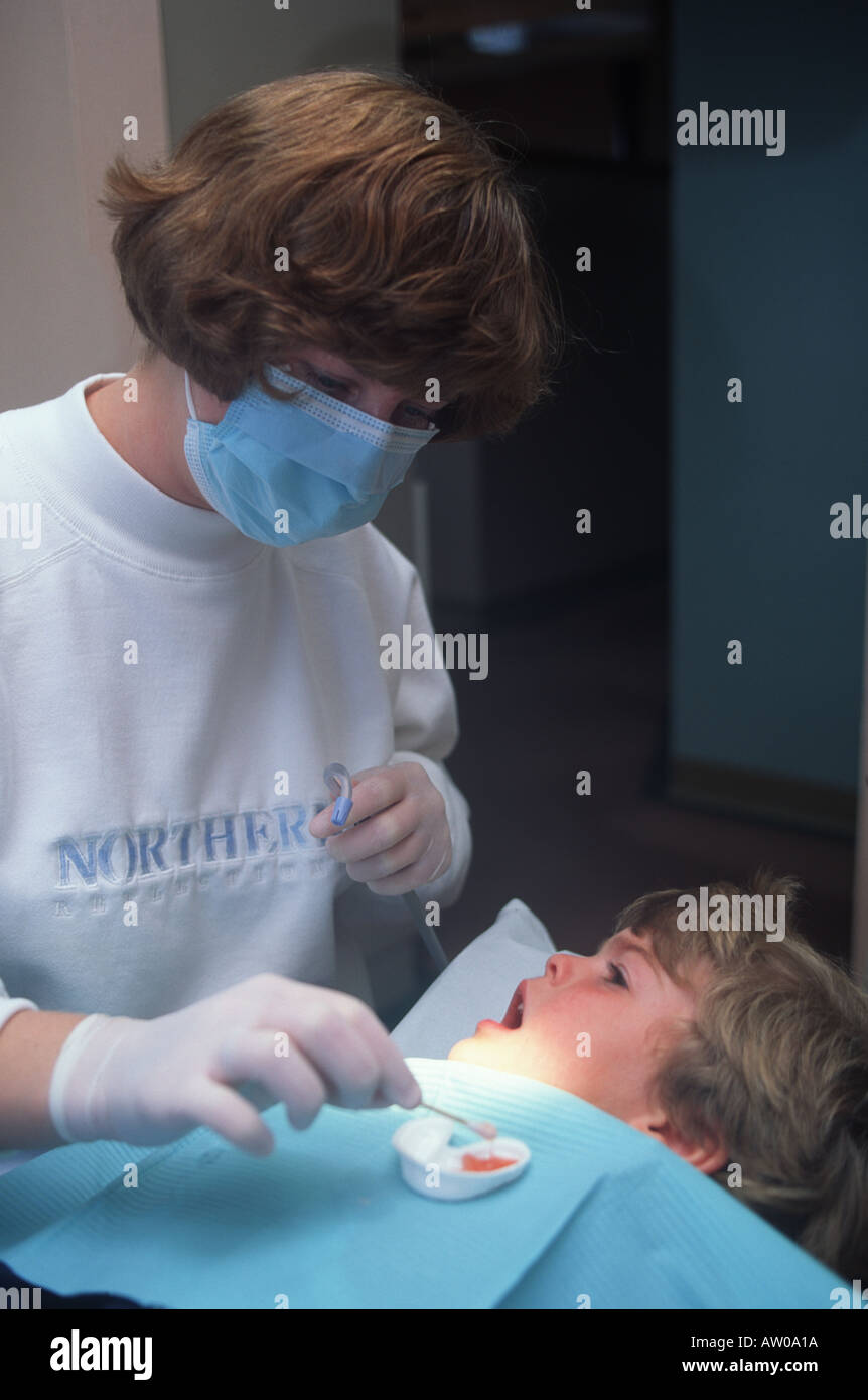 Dental hygenist cleans boys teeth Stock Photo