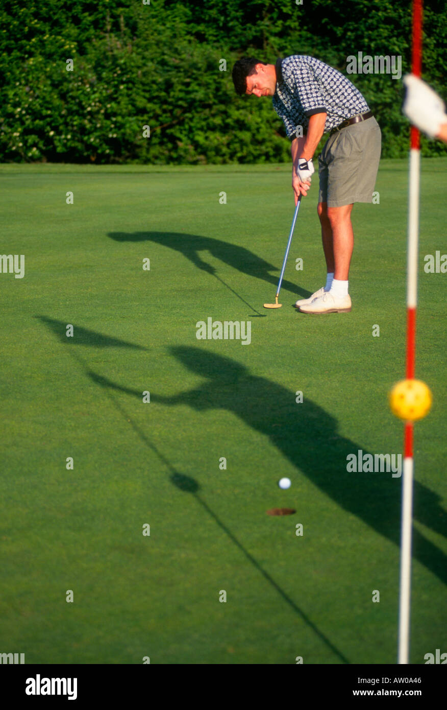 Canada Victoria athletic 20 something golfer putts ball shadow of partner on grass Stock Photo