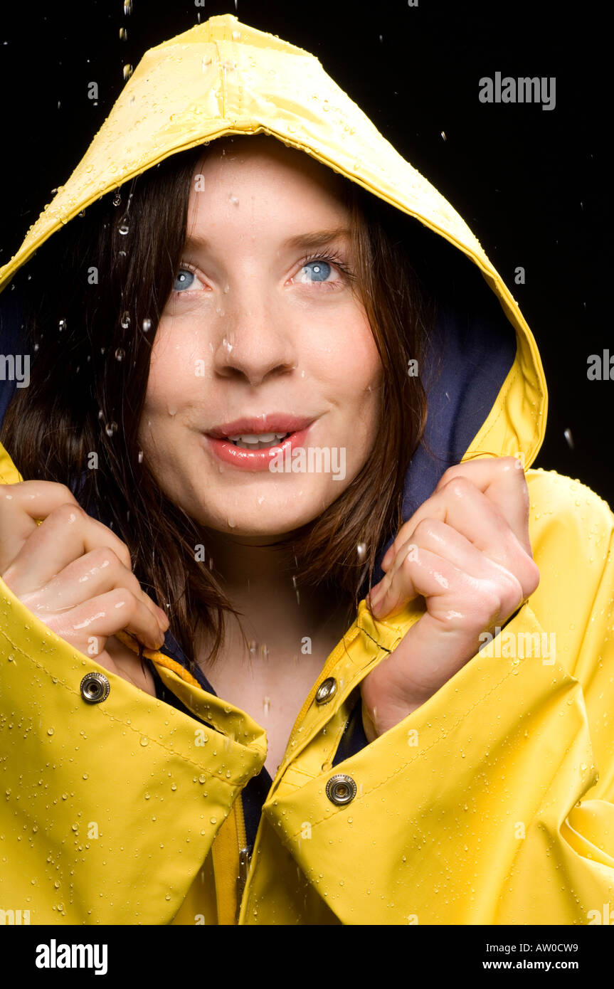 portrait of young woman wearing yellow raincoat in the rain Stock Photo