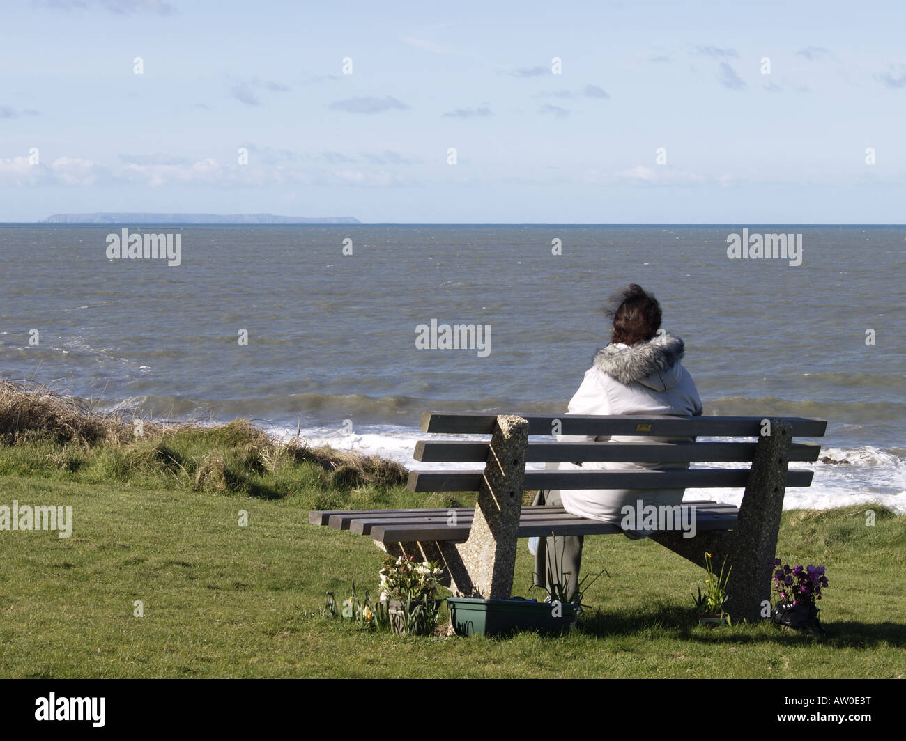 Woman sat on park bench looking out to sea at Lundy island Stock Photo