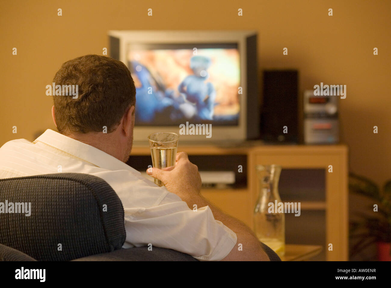 TV VIOLENCE 3 A man watching war film on a television. Hes drinking liquid in a glass. Stock Photo