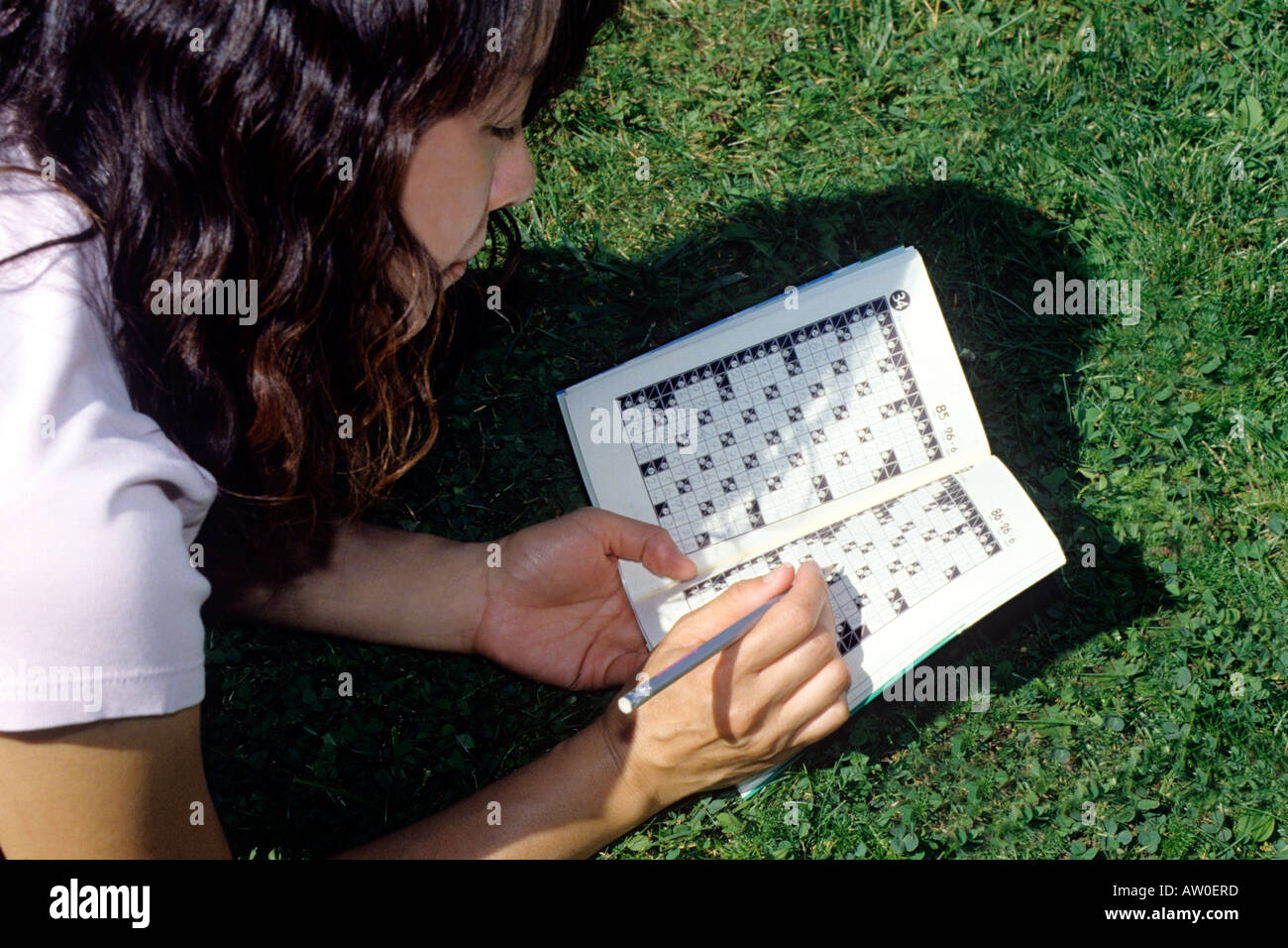 japanese woman lying in grass solving kakuro crossword Stock Photo