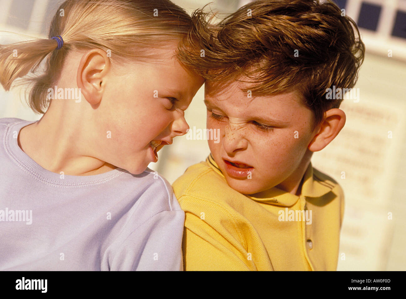portrait of a boy and a girl sitting back to back pulling faces Stock ...