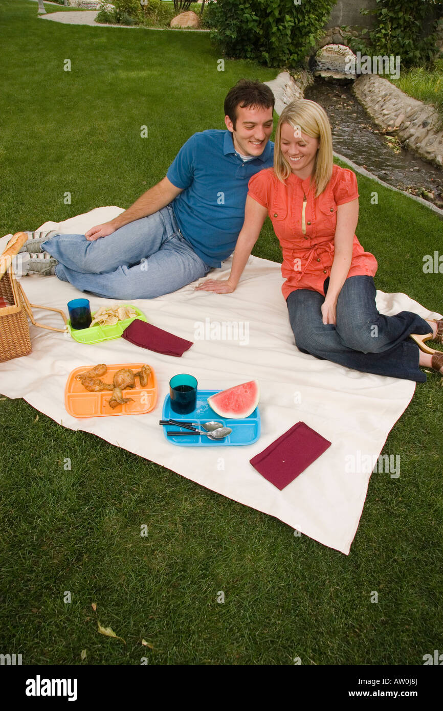 Young couple enjoying a picnic in the park Stock Photo - Alamy