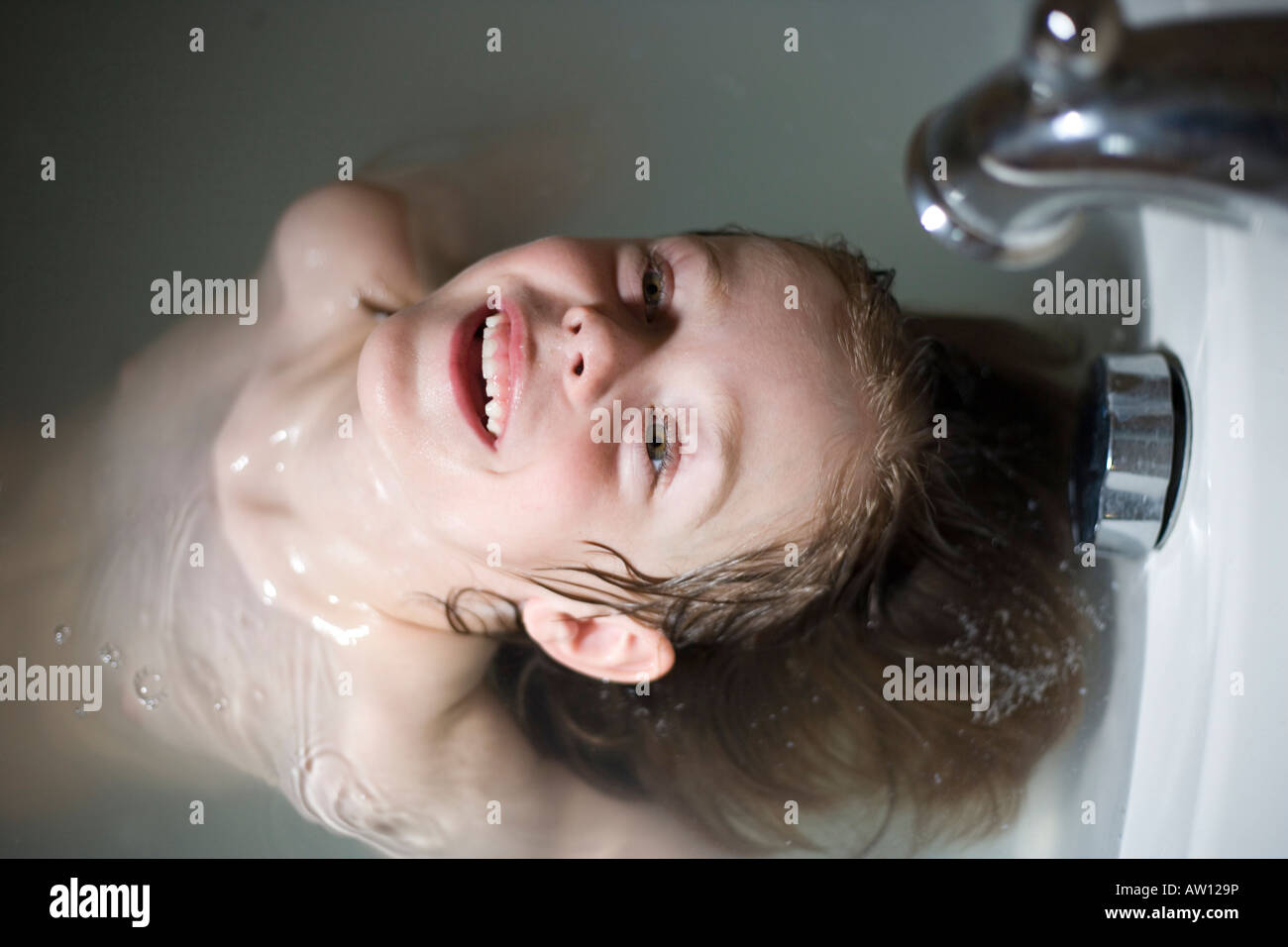 five year old child in bath tub rinsing hair under faucet Stock Photo