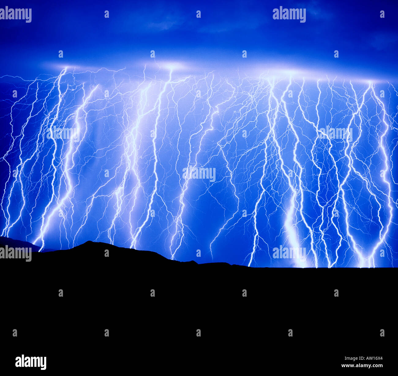 Blue Graphic Sky Lightning and monsoon rainstorm shower produces multiple Skystrikes  from  dark clouds in the Rincon Mountai Stock Photo