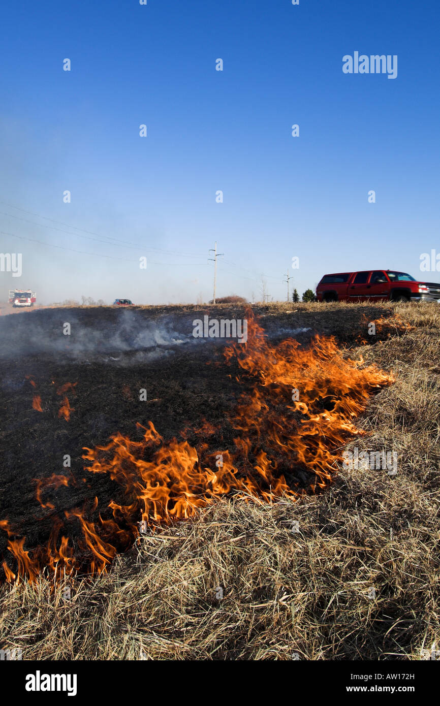 A grass fire burning along highway. Stock Photo