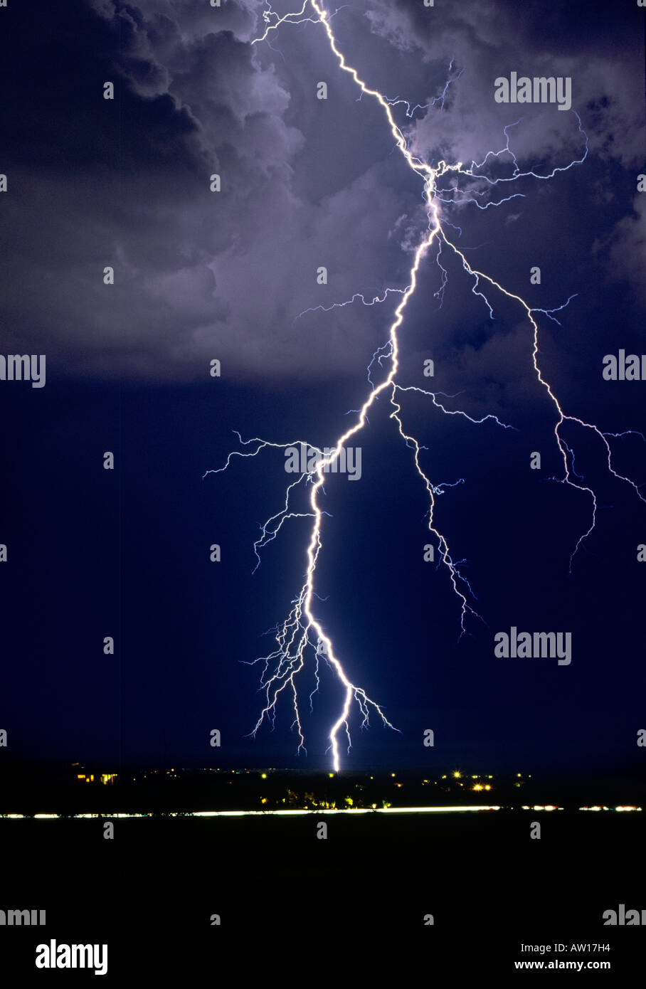 Lightning bolts strike dramatically from a dark and stormy sky. The clouds are ominous against the dark night. Jeff Smith Stock Photo