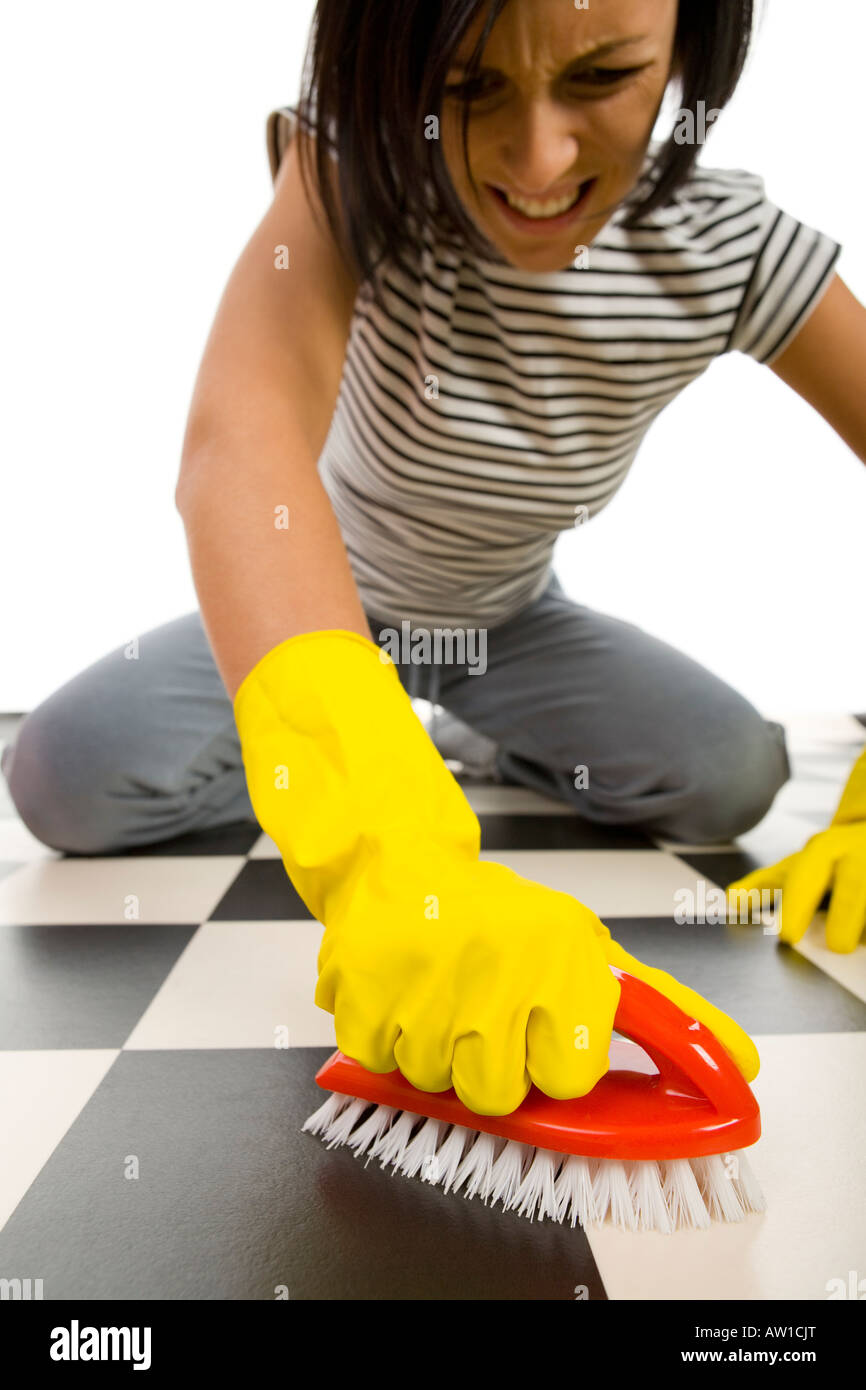 Young woman in yellow rubber gloves kneeling and scrubs the floor