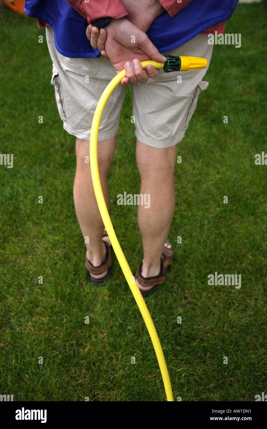 Man waiting with water hose pipe behind him Stock Photo
