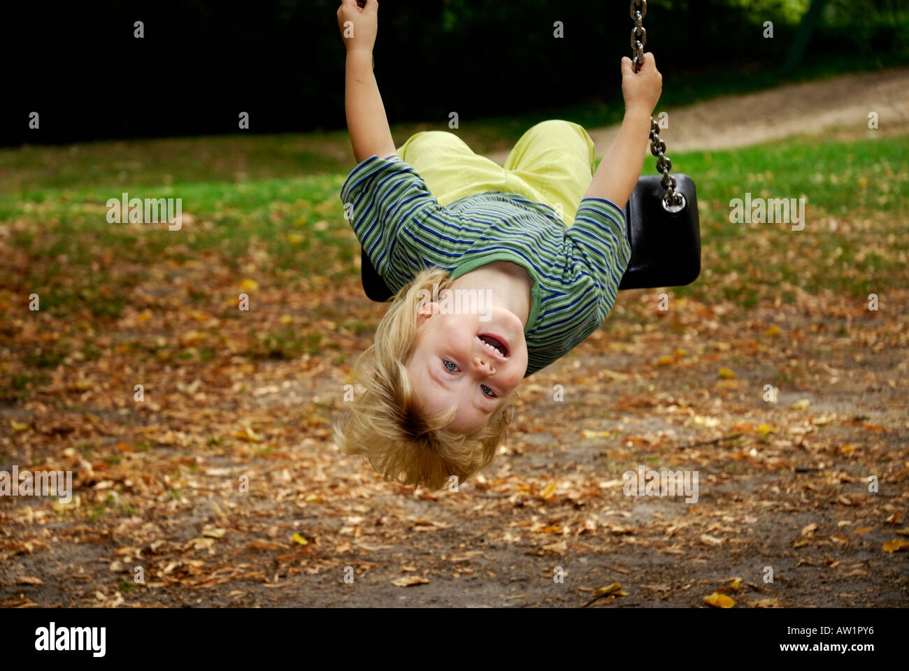 Little girl swinging upside down in a playground Stock Photo