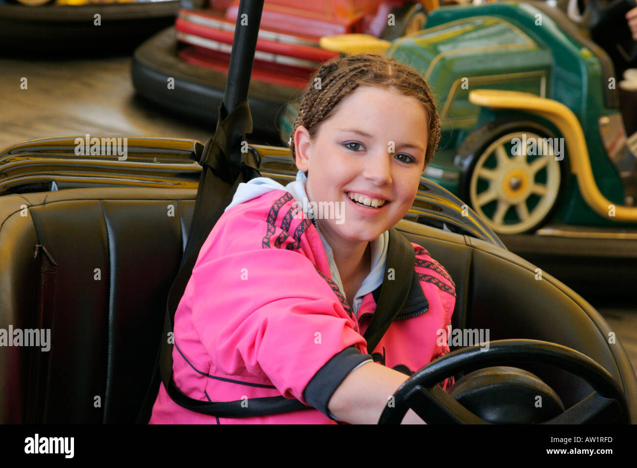 Happy smiling teenage girl on dodgems at fairground Stock Photo