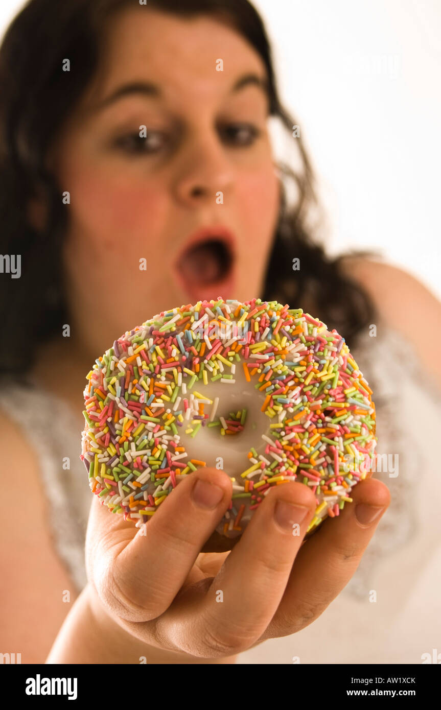 Fat overweight young woman guiltily eating a sweet donut Stock Photo