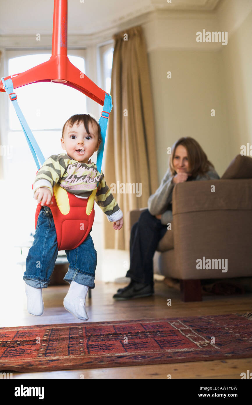 Eight month old girl in baby bouncer with mum watching on Stock Photo