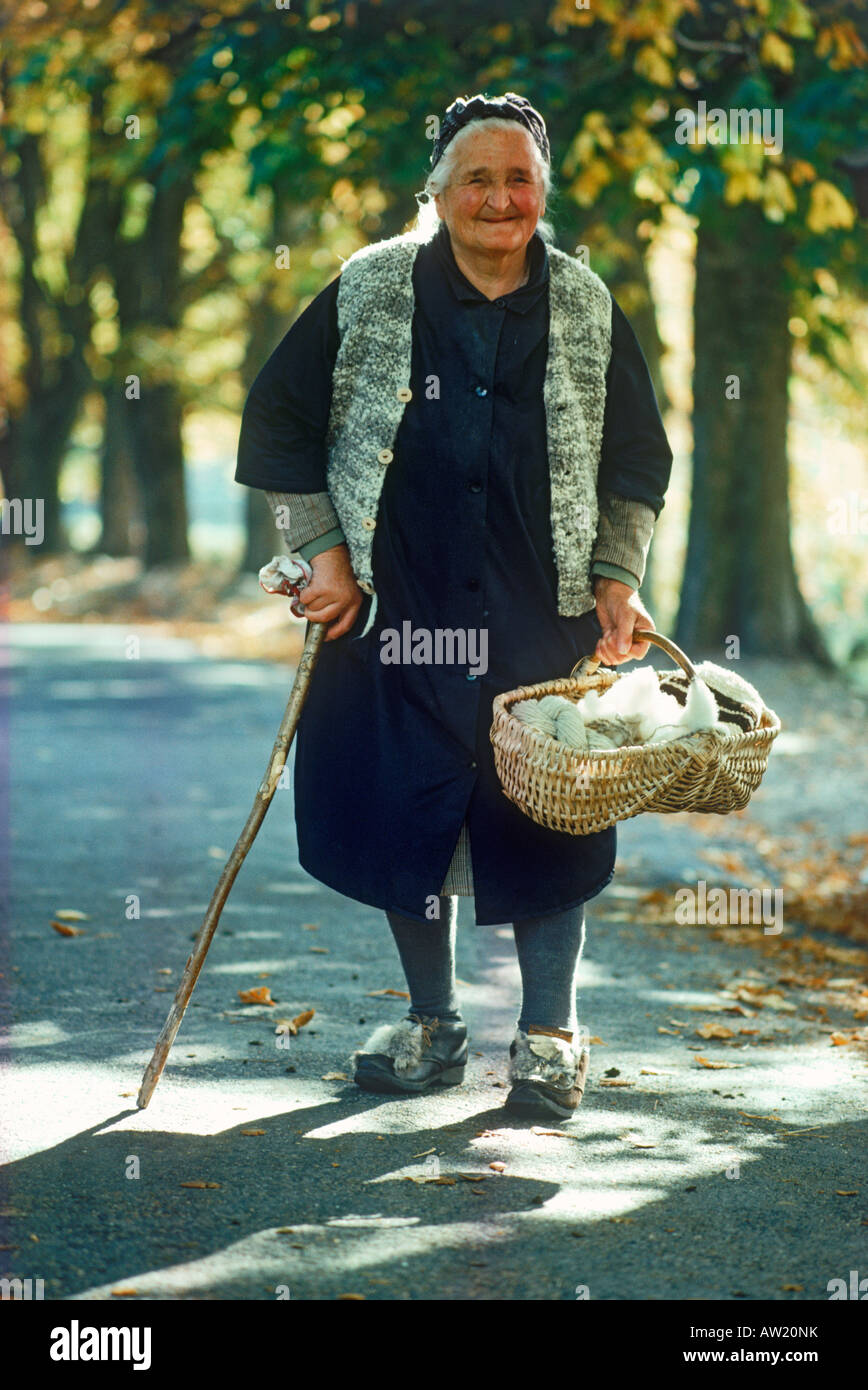Old Italian woman walking country road with basket of yarn to village near Swiss border Stock Photo