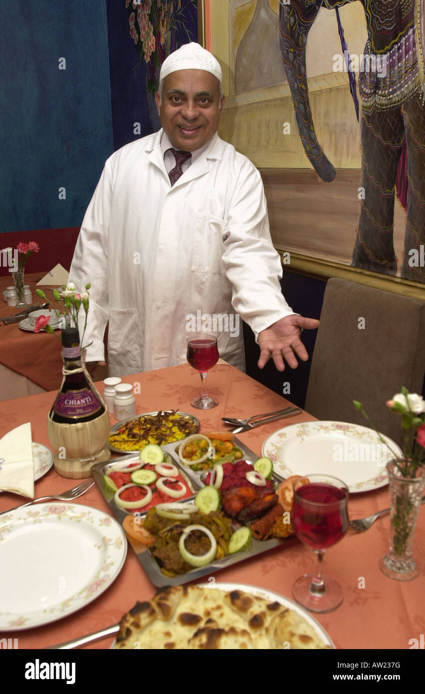 Restauranteur welcomes you to a table in his curry house Stock Photo