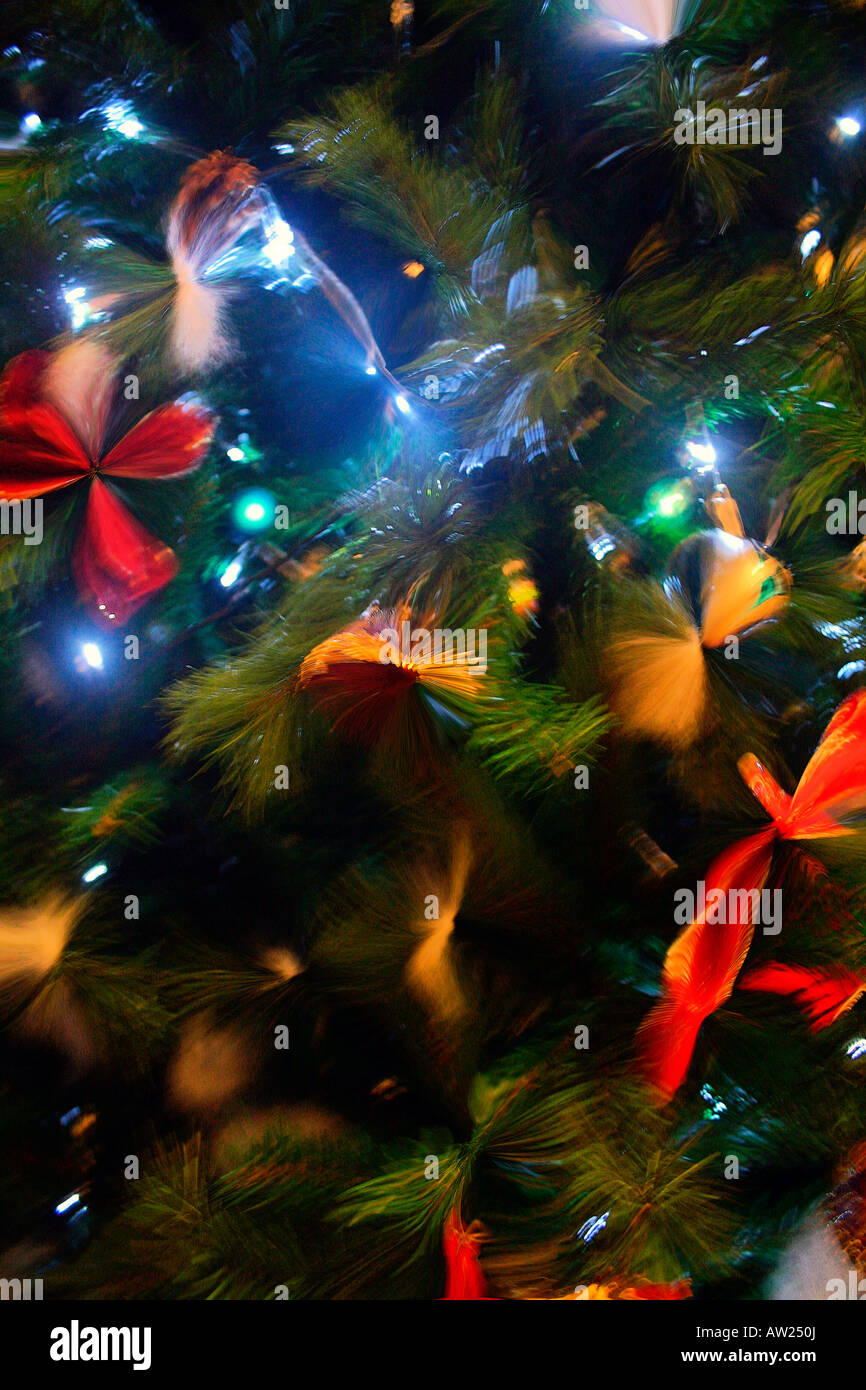 Festive glow of baubles lights ribbons ornaments bells on a Christmas tree seen through frosted glass Stock Photo