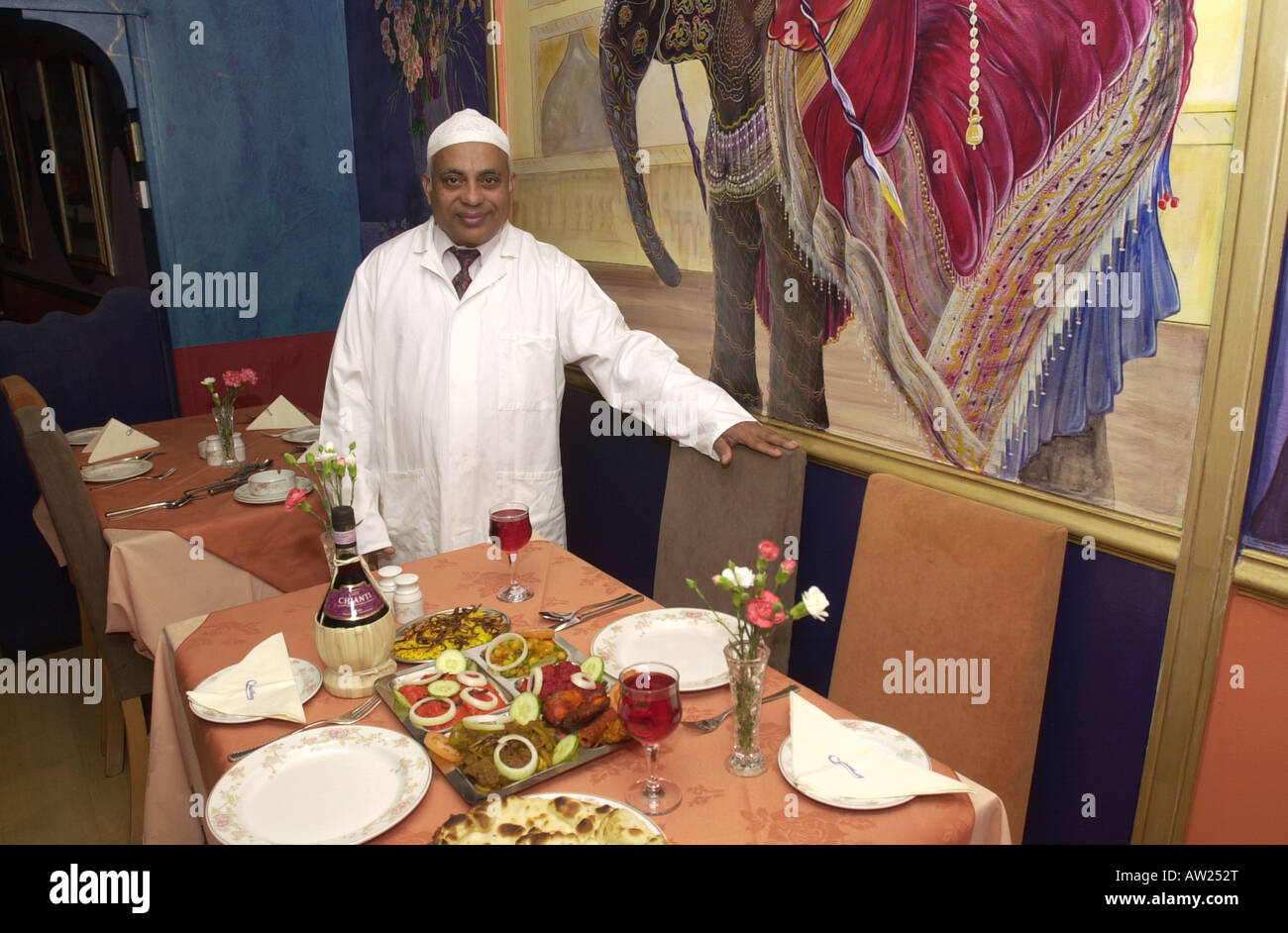 Restauranteur welcomes you to a table in his curry house Stock Photo