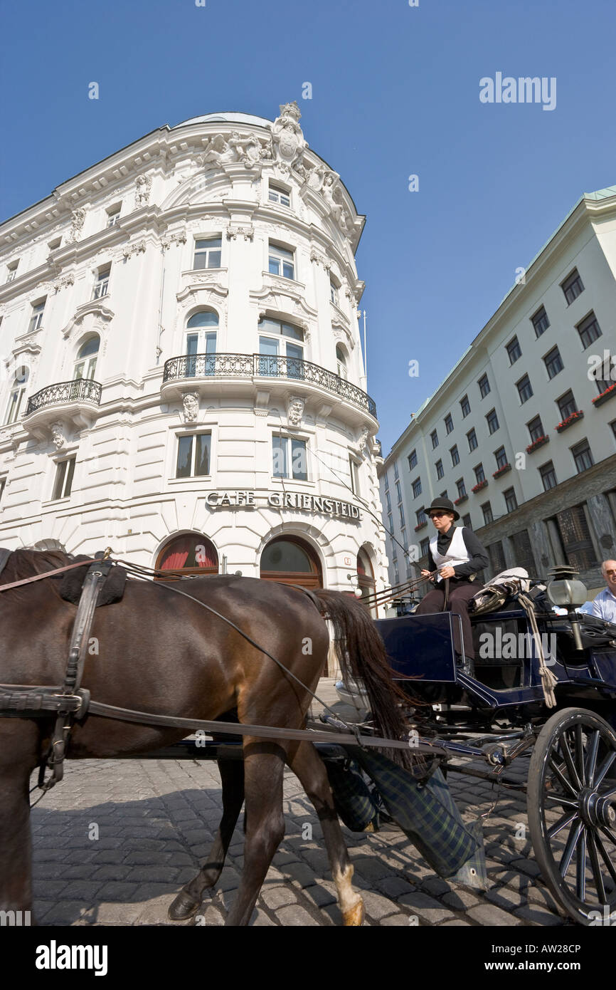 Horse drawn carriage Fiaker with female driver passing Cafe Griensteidl of Vienna Austria Stock Photo