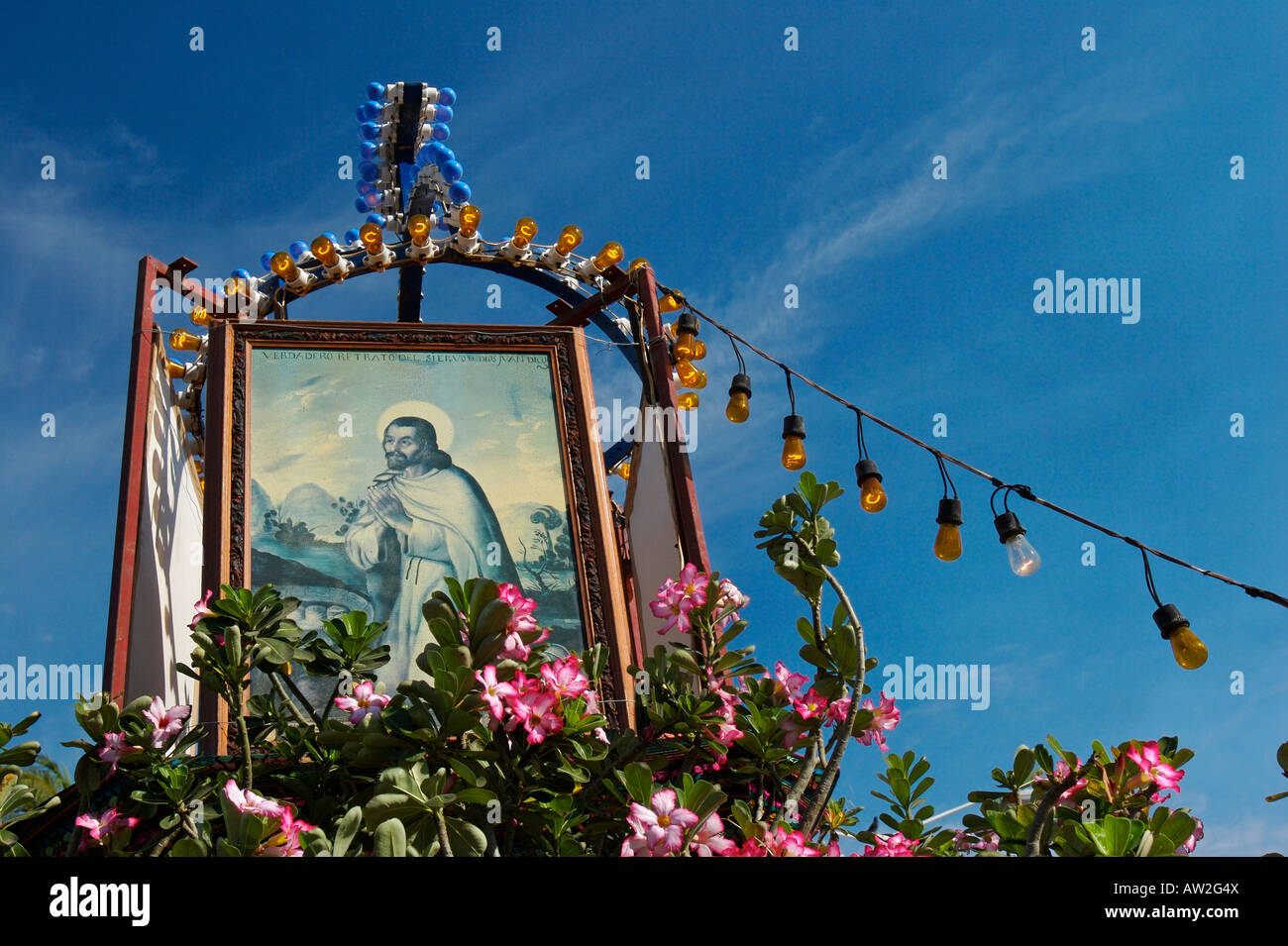 An image of  Jesuschrist on top of some kind of altar of flowers in the street. Stock Photo
