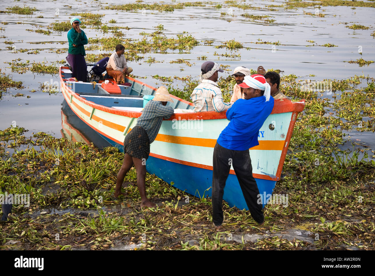 Fishermen standing beside their boat, Fort Cochin, Cochin, Kerala, India Stock Photo