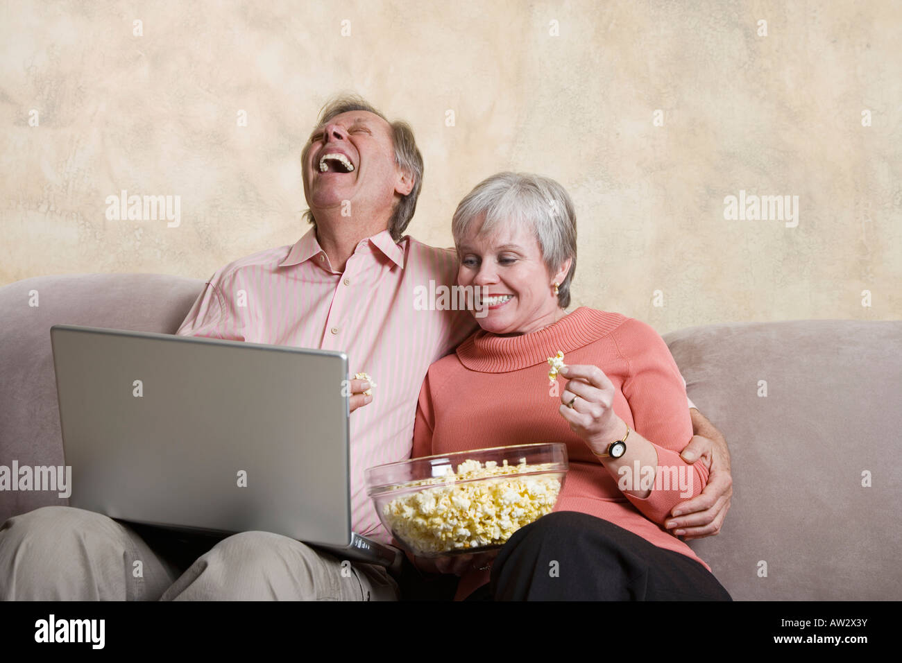 senior man and woman watching computer laptop, eating popcorn Stock ...