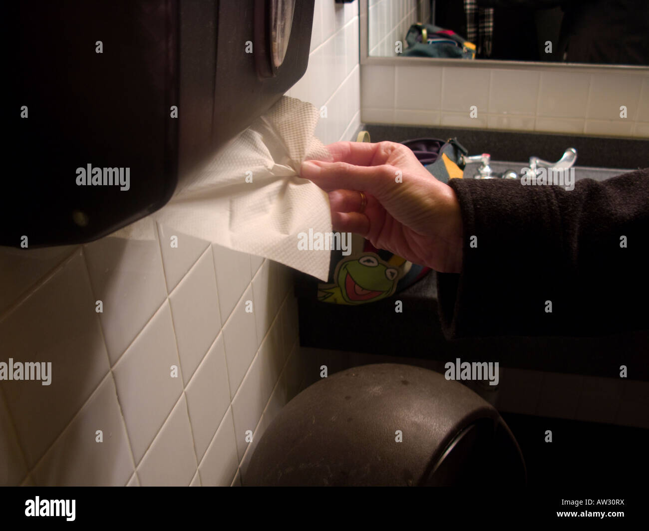 A caucasian woman extracts a paper towel after washing her hands in a public restroom. USA. Stock Photo