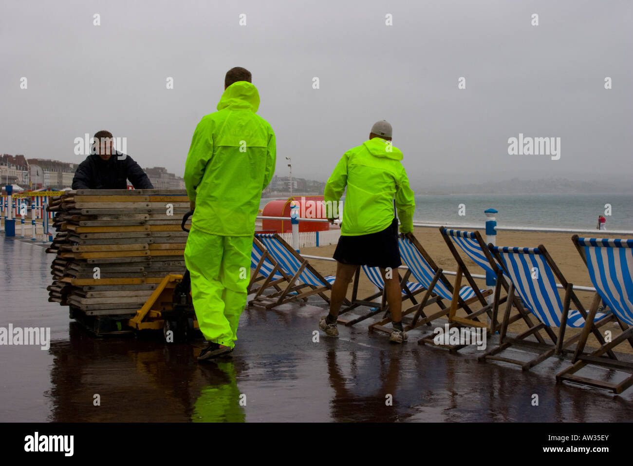 Deck chair attendants in high visibility jackets collect deckchairs