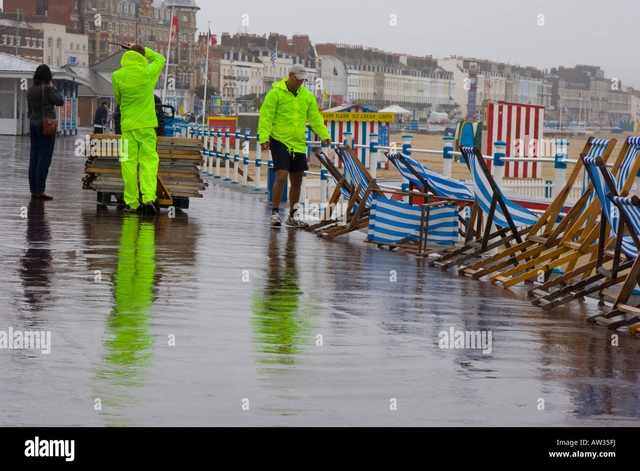 Deck chair attendants in high visibility jackets collect deckchairs