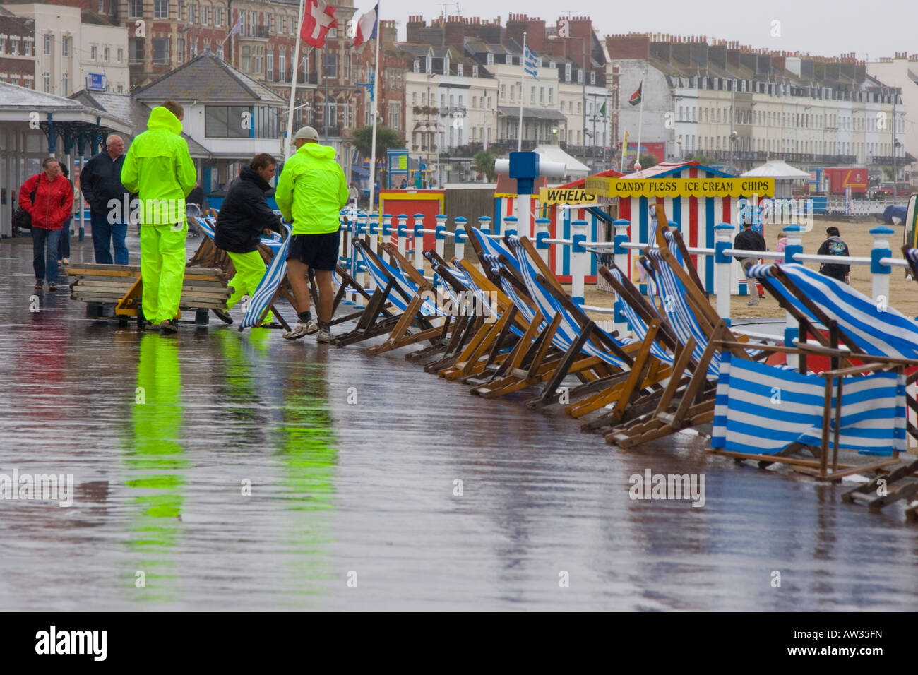 Deck chair attendants in high visibility jackets collect deckchairs