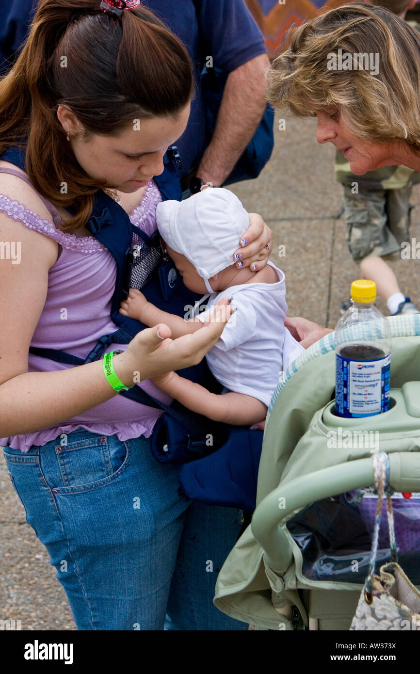 Teenage Girl with Simulated Real Baby, Helped by Mom for Social Studies Class Stock Photo